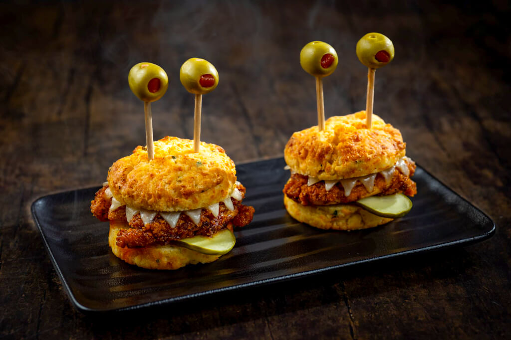 Two ‘monster’ chicken biscuit sliders with olive ‘eyes’ on skewers and pickle slices at Jock Lindsey’s Hangar Bar.