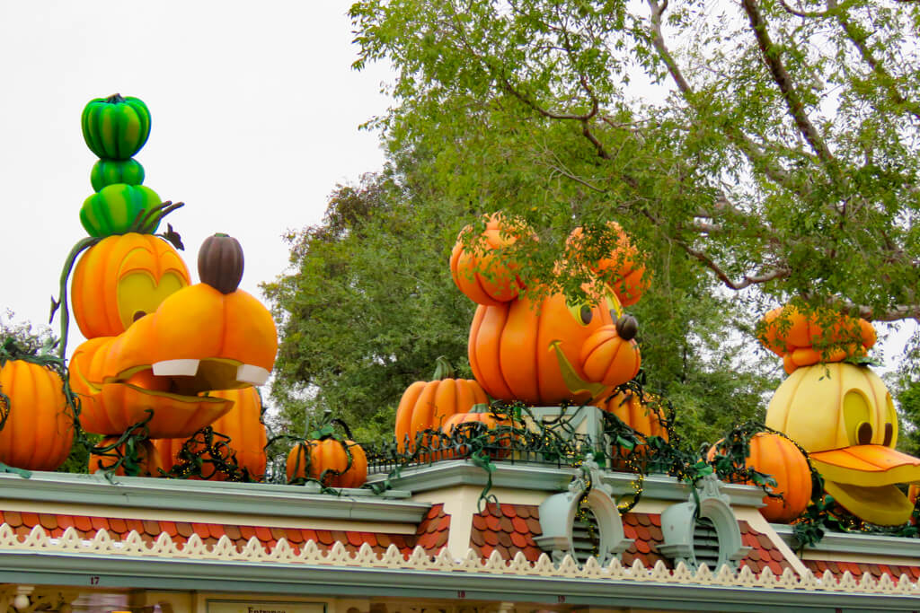 Goofy, Minnie, and Donald pumpkin sculptures decorate the Disneyland entrance roof during Halloween Time.