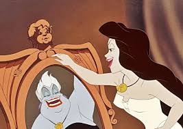 Vanessa grins at a mirror showing Ursula’s reflection as the seashell necklace glows.